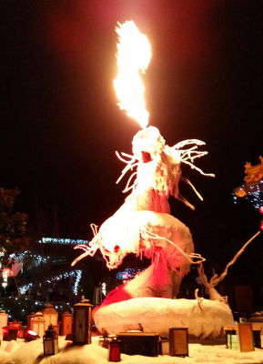 Feuerspeiende Drachenfigur umgeben von Lampen in Winterlandschaft